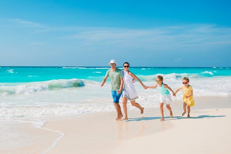 Eine Familie mit zwei Kindern läuft fröhlich durch die Wellen am Strand