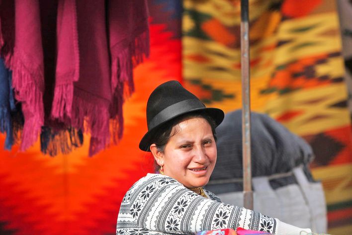 Frau aus Otavalo in traditioneller Tracht mit Hut und farbigen farbigen Textilien