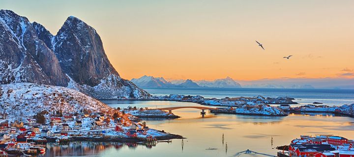 Blick auf das Fischerdorf Lofoten bei einem Sonnenaufgang im Hintergrund