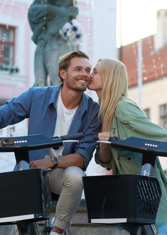 Junges Paar auf Fahrrädern vor historischem Stadtplatz in Tartu, Estland