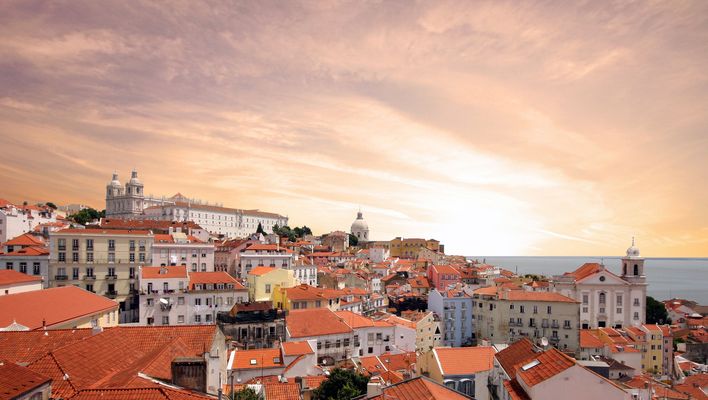Altstadt von Lissabon bei Sonnenuntergang mit roten Dächern und warmem Licht