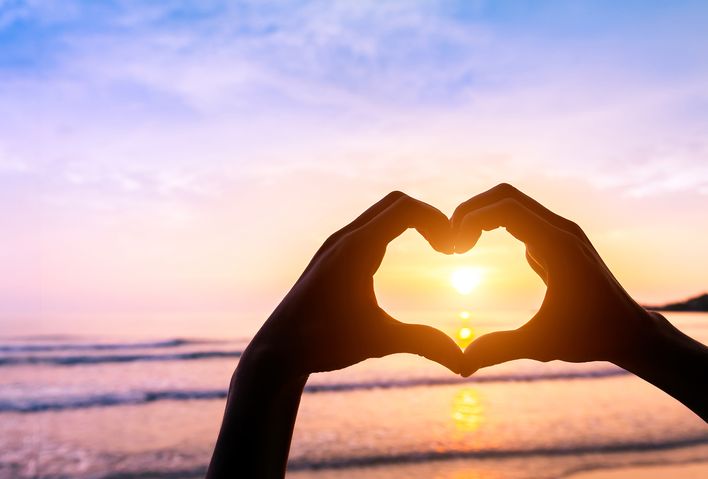 Mit Händen geformtes Herz am Meer
