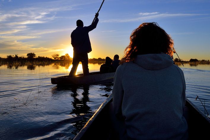 Tourist im Boot im Okavango-Delta bei Sonnenuntergang in Botswana