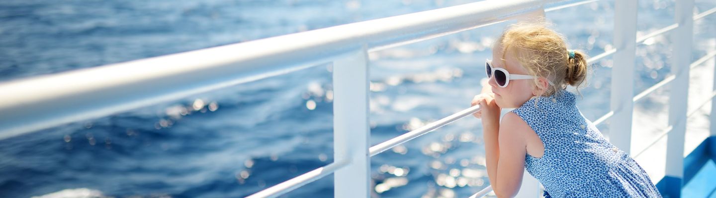 Ein Mädchen steht an der Reling eines Kreuzfahrt-Schiffes