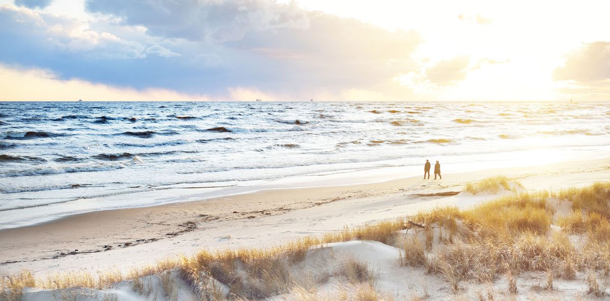 Blick auf einen Strand mit Dünen und einem Paar in der Ferne