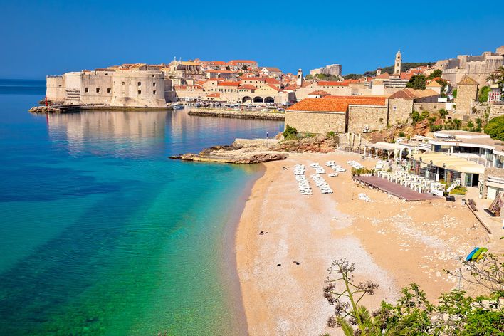 Strand Banje in Dubrovnik, Kroatien, mit Blick auf die Altstadtmauern und das Adriatische Meer