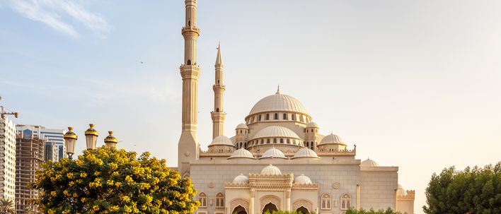 Große Moschee in Sharjah mit Minaretten, Kuppeln und gepflegter Gartenanlage