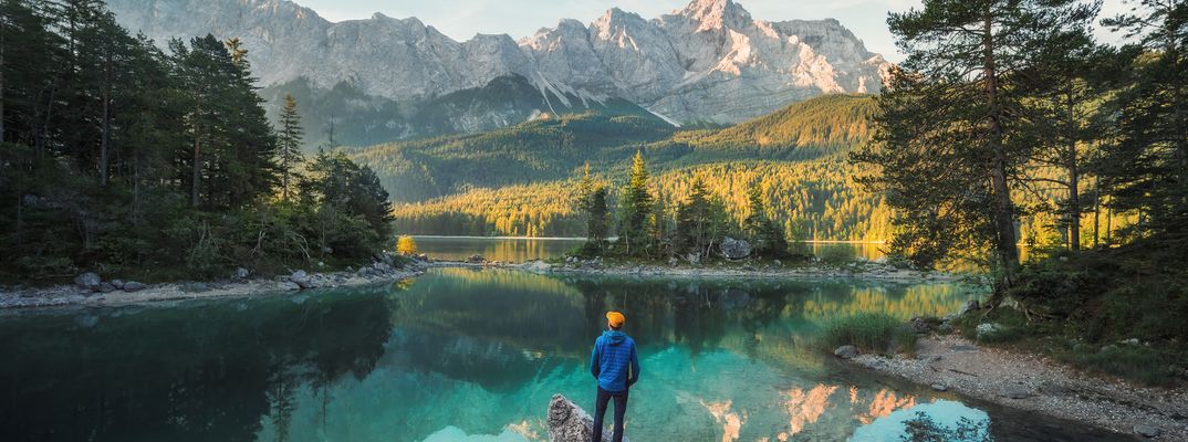 Mann steht am Eibsee und genießt den Ausblick auf die Alpen