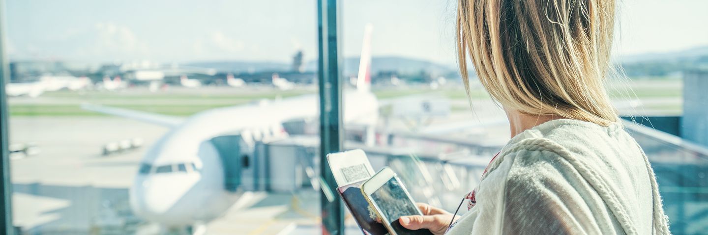 Frau am Flughafen und schaut auf Flugzeug