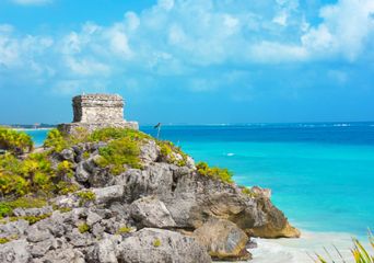 Felsige Bucht bei Tulum mit weißem Sand, Palmen und klarem Karibikmeer