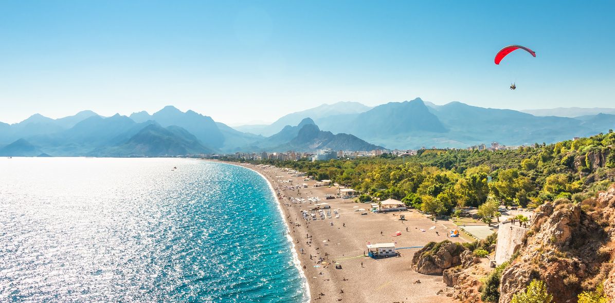 Weiter Sandstrand mit türkisblauem Meer und Booten bei Alanya an der türkischen Riviera