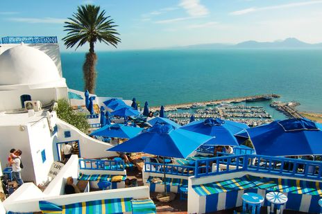 Typische weiße Häuser mit blauen Fenstern und blauen Sonnenschirmen in der Stadt Sidi Bou Said in Tunesien