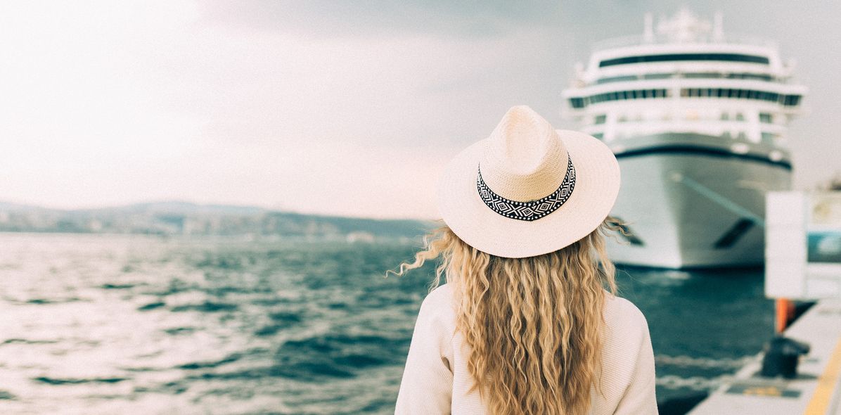 Frau steht vor einem Kreuzfahrtschiff