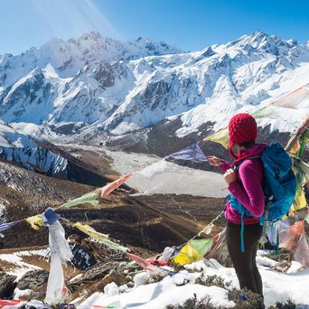 Frau genießt den Ausblick auf die schneebedeckte Berglandschaft in Nepal bei einer Wanderung