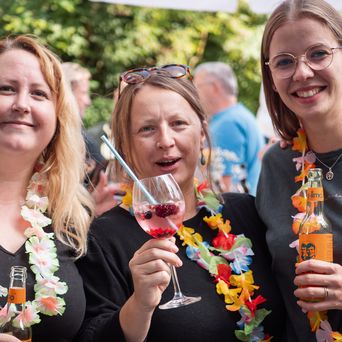 Mitarbeiter Daniel, Daniela und Julia mit Hawaii-Ketten auf dem Sommerfest 2024