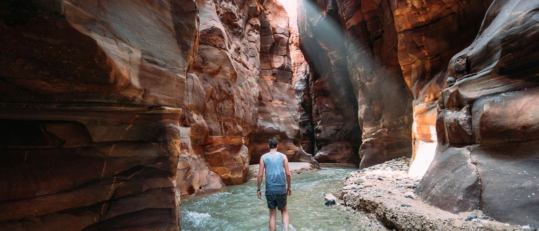 Ein Mann watet durch den Bachlauf in der Schlucht von Wadi Mujib in Jordanien