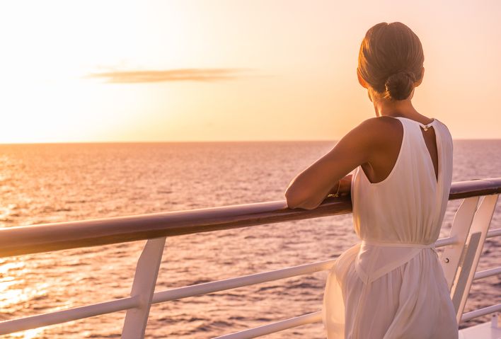 Frau bei Sonnenuntergang auf einem Kreuzfahrtschiff