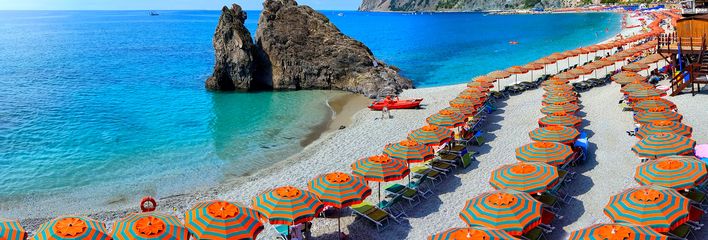 Strand in Cinque Terre mit bunten Sonnenschirmen und Küstenblick