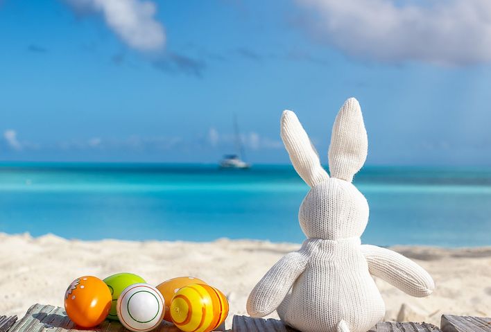 Osterhase aus Stoff und bunte Eier am Strand